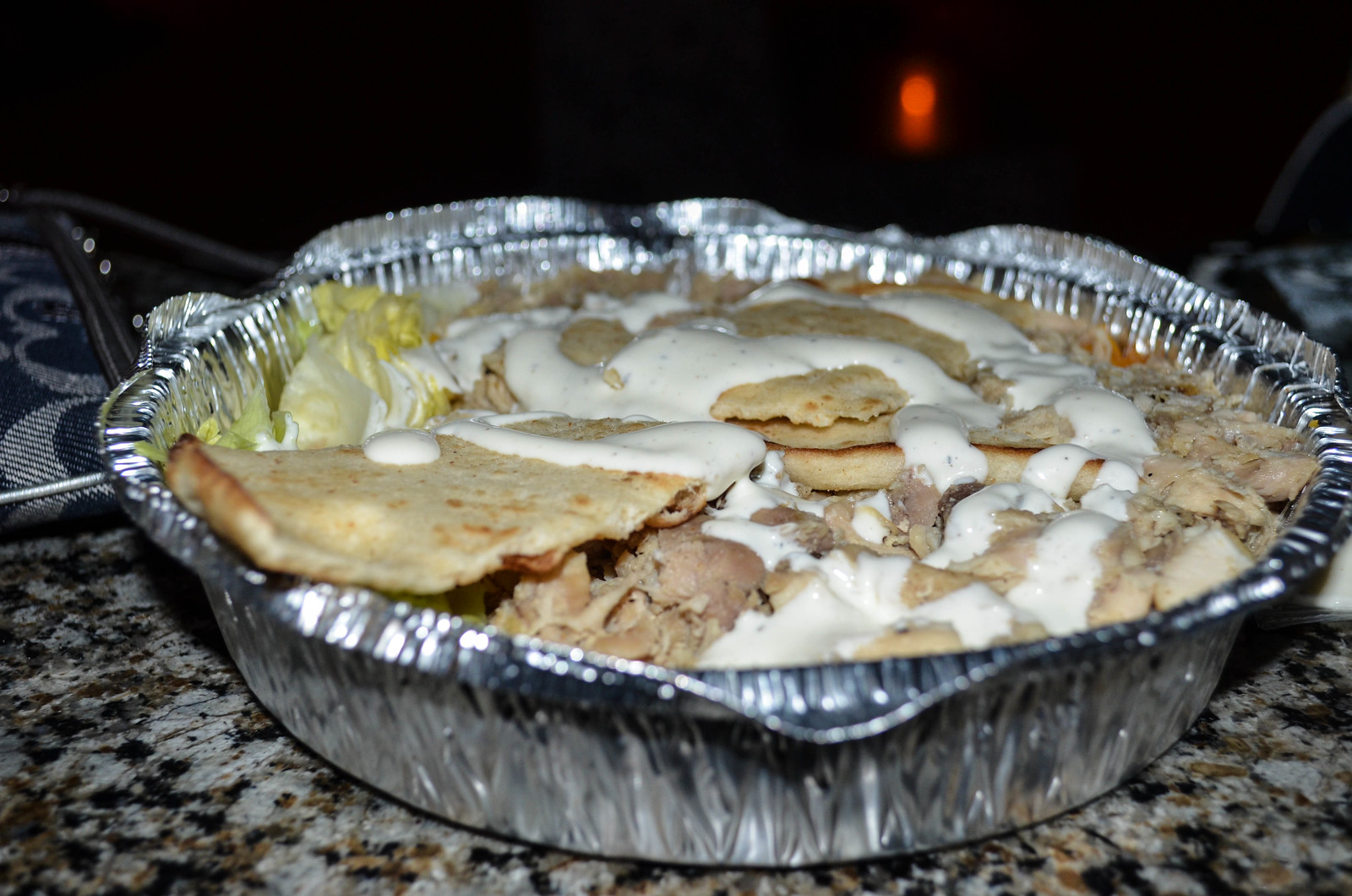 The Halal Guys のアルミ容器入りチキン・オーバー・ライス、白いソースたっぷり