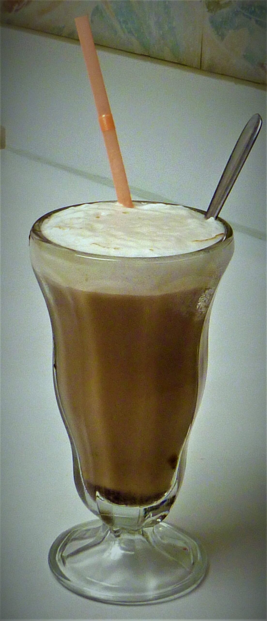 脚付きのソーダグラスに入った泡立つチョコレートのエッグ・クリームとストロー