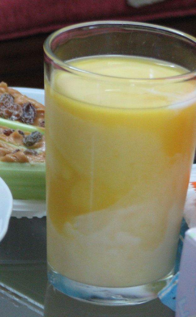 グラスに入ったオレンジジュースとミルクを合わせた淡いオレンジ色の飲み物