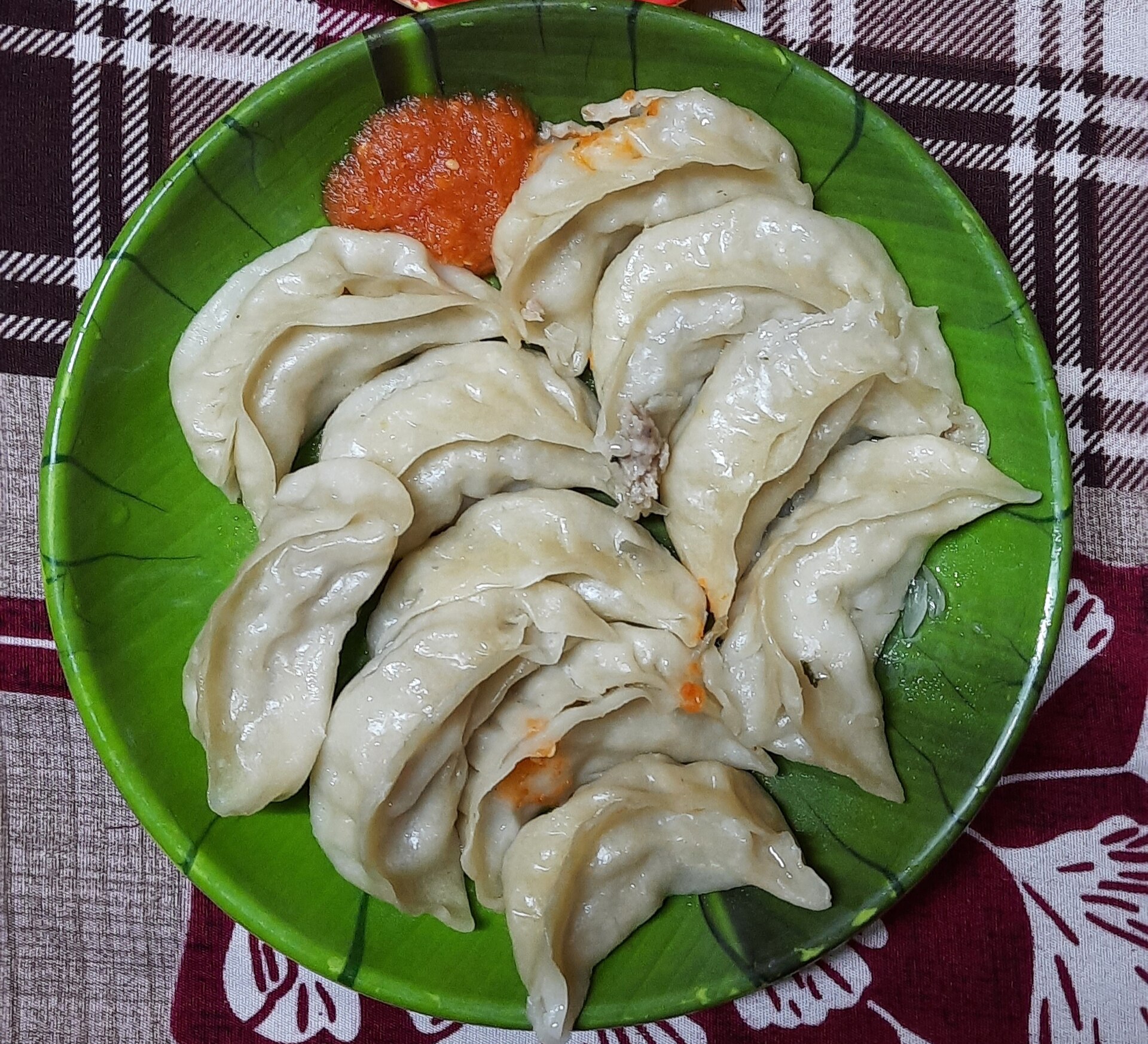 木の葉型の皿に盛った蒸しモモとトマトのアチャール