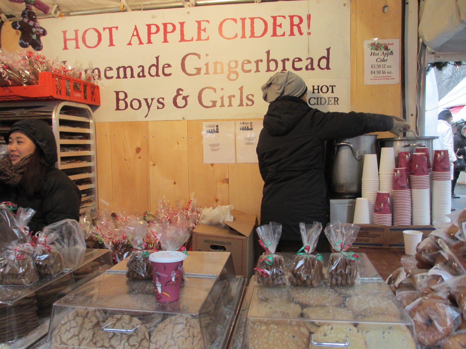 HOT APPLE CIDER! の看板を掲げた市場の屋台と紙コップ