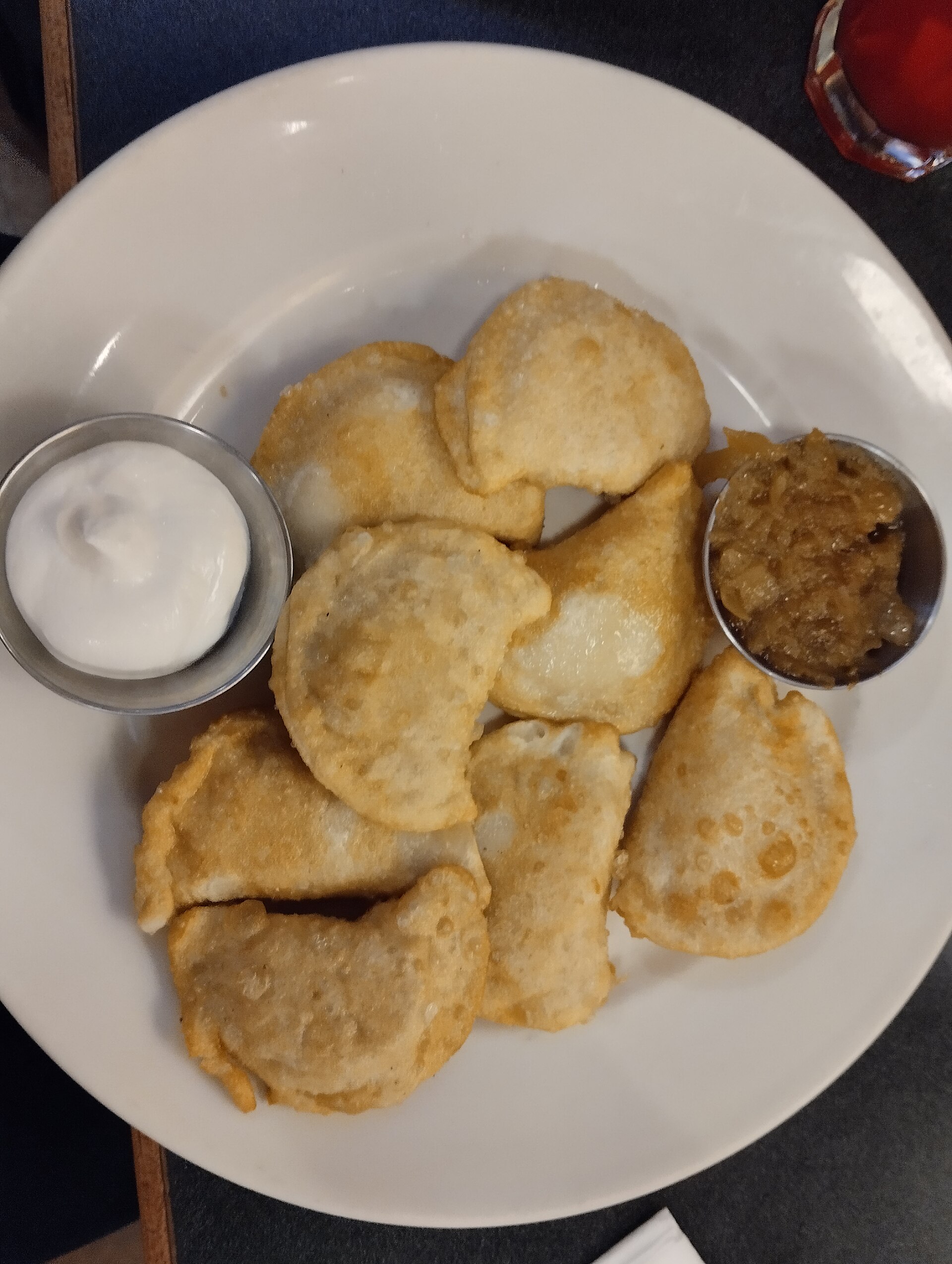 Veselka の皿に盛った焼いたピエロギ、サワークリームと炒め玉ねぎ