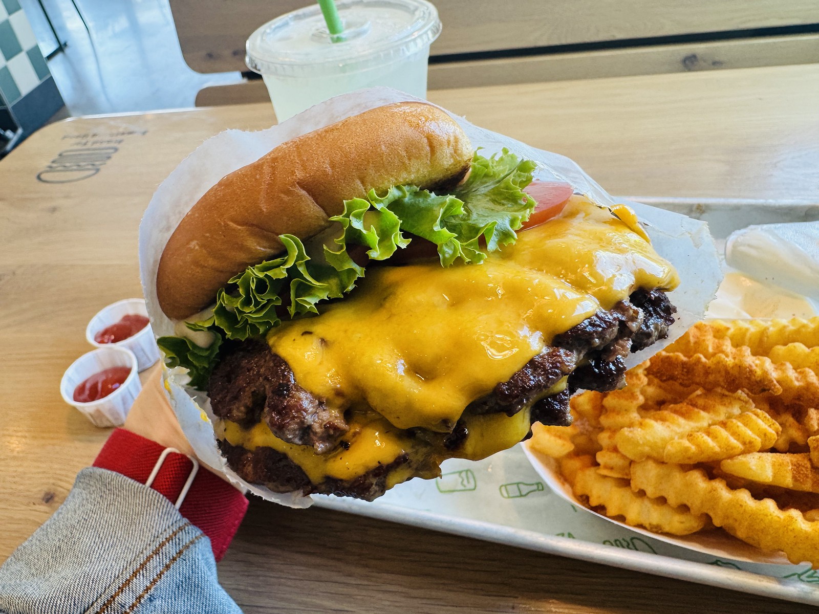 テーブルに置いたシャックバーガーとフライ、ケチャップの小カップ