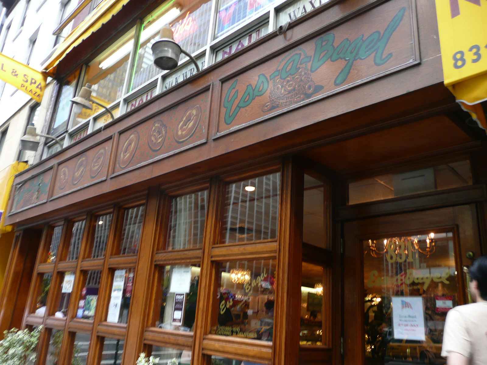 緑の看板に筆記体「Ess-a-Bagel」の木枠の店先を見上げて