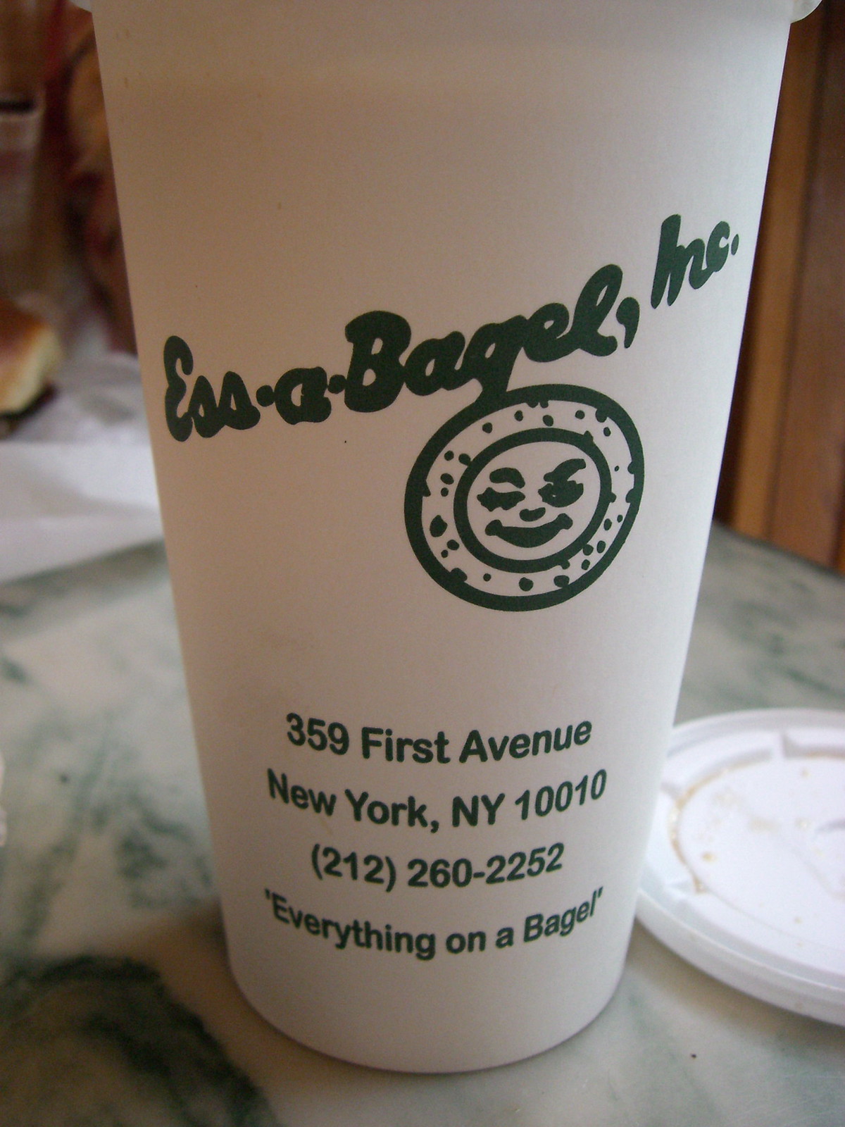 店のロゴと住所が入った Ess-a-Bagel の紙カップのコーヒー