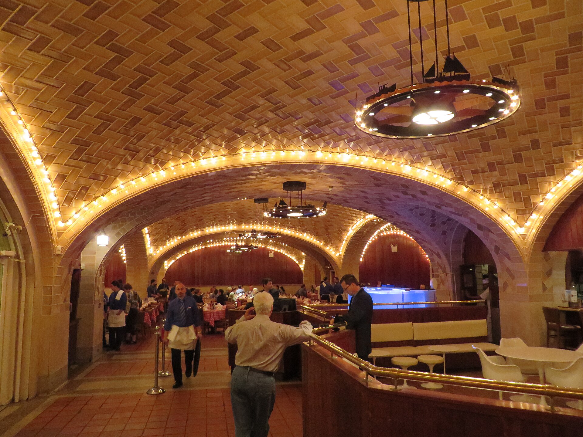 タイル張りのヴォールト天井と電球の縁取りが続く Grand Central Oyster Bar の店内
