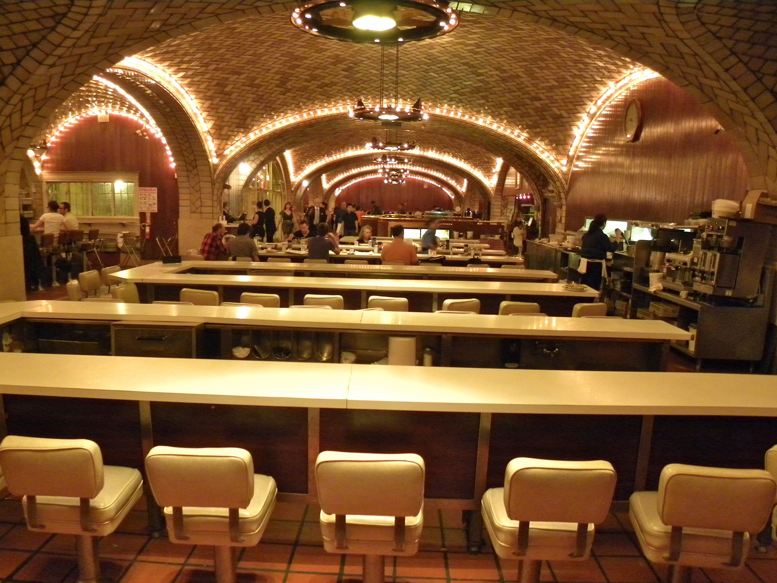 白いスツールが並ぶ Oyster Bar のカウンター席とアーチ天井