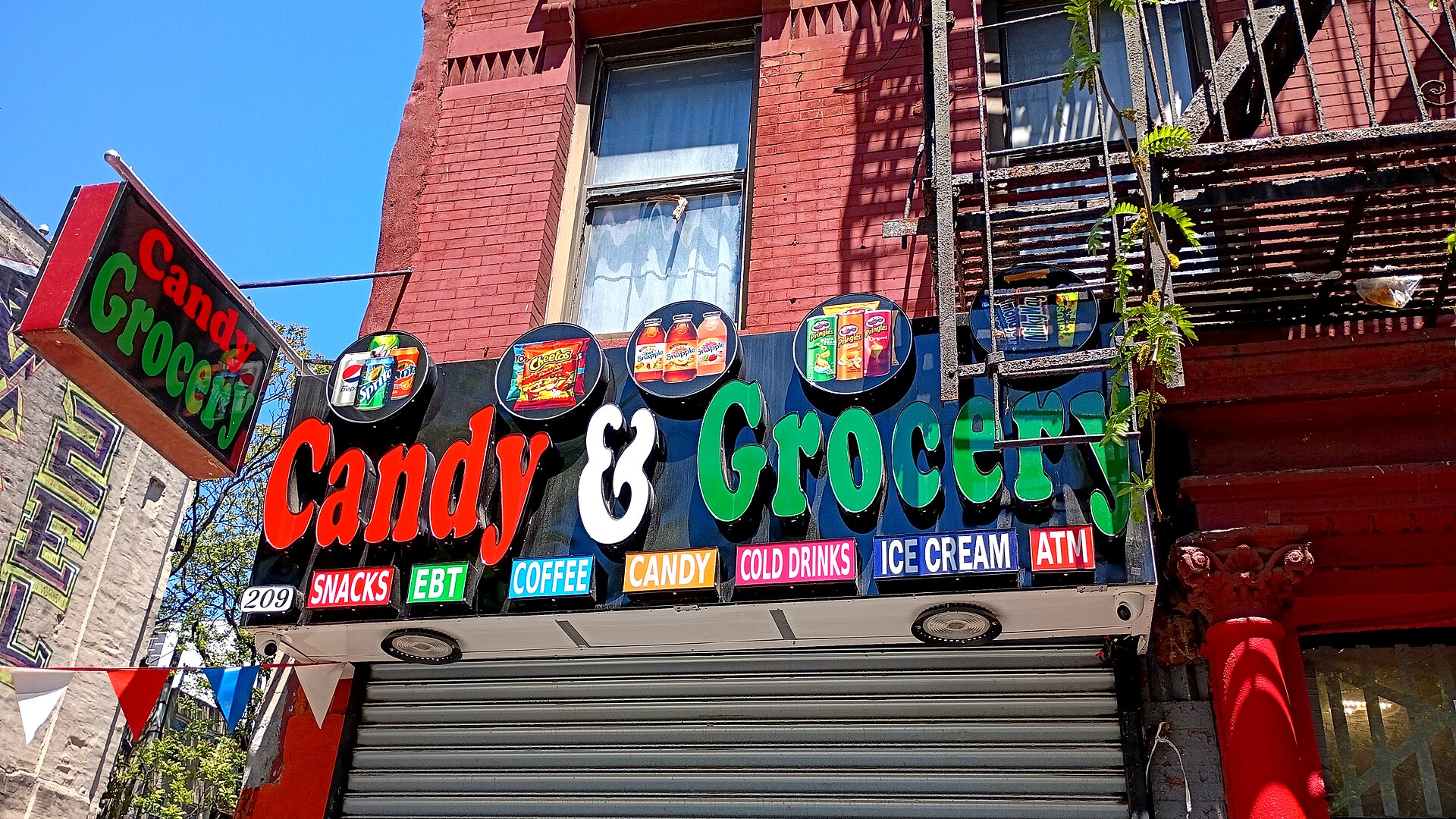 イーストハーレムのボデガ、赤い建物に派手な「Candy & Grocery」の看板