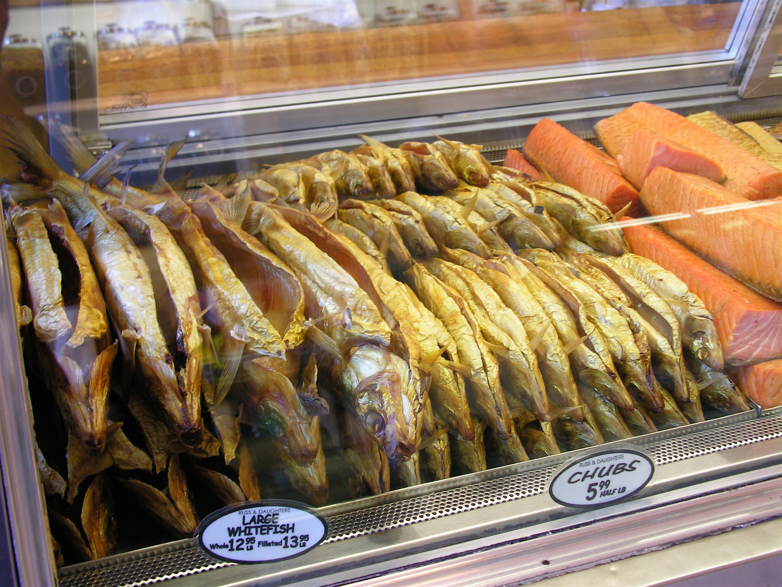 ガラスケースに並ぶ金色の燻製の魚（ホワイトフィッシュ）とサーモン