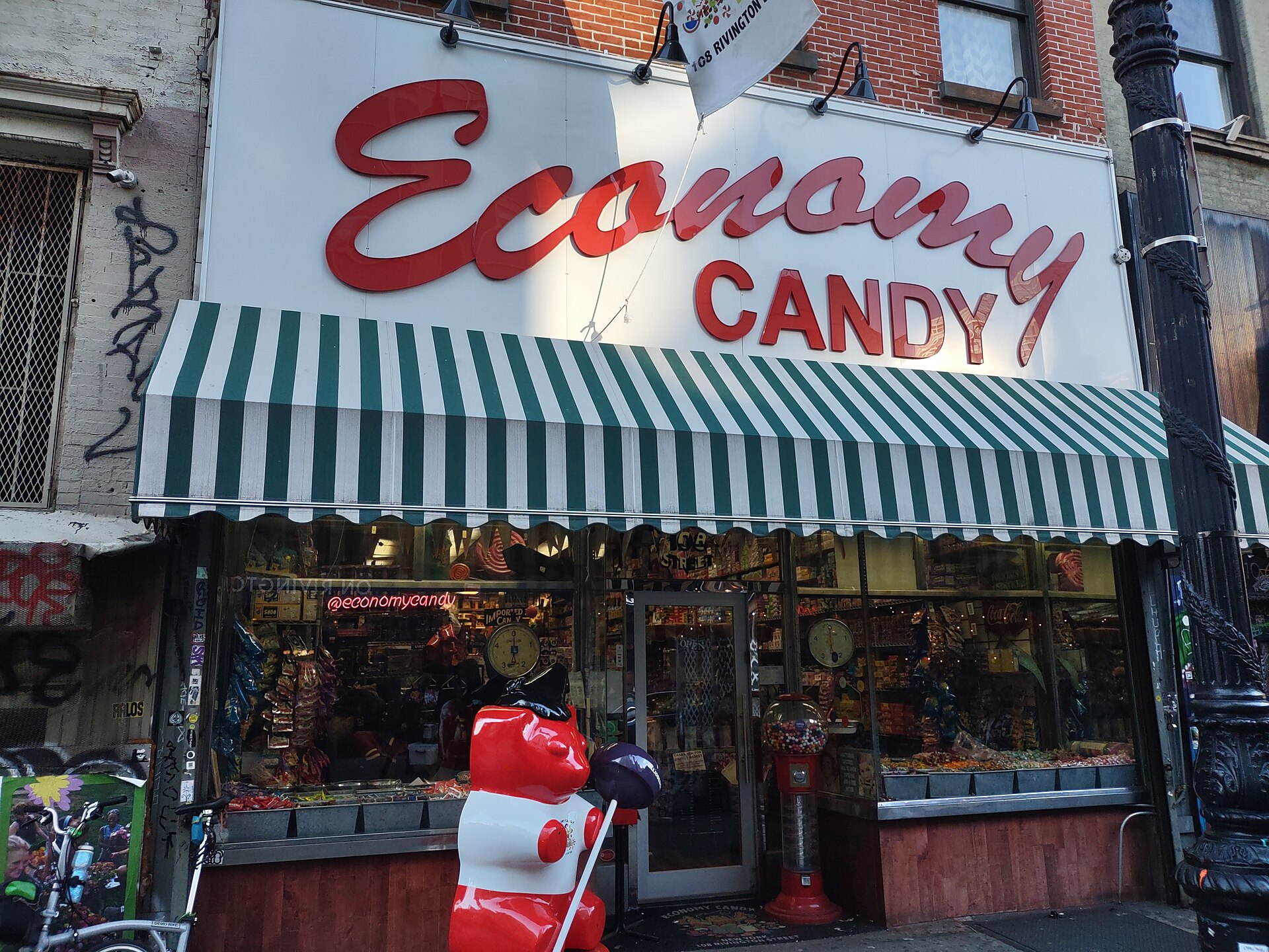 赤い筆記体の「Economy Candy」看板と緑白の日よけ、菓子が並ぶ店先