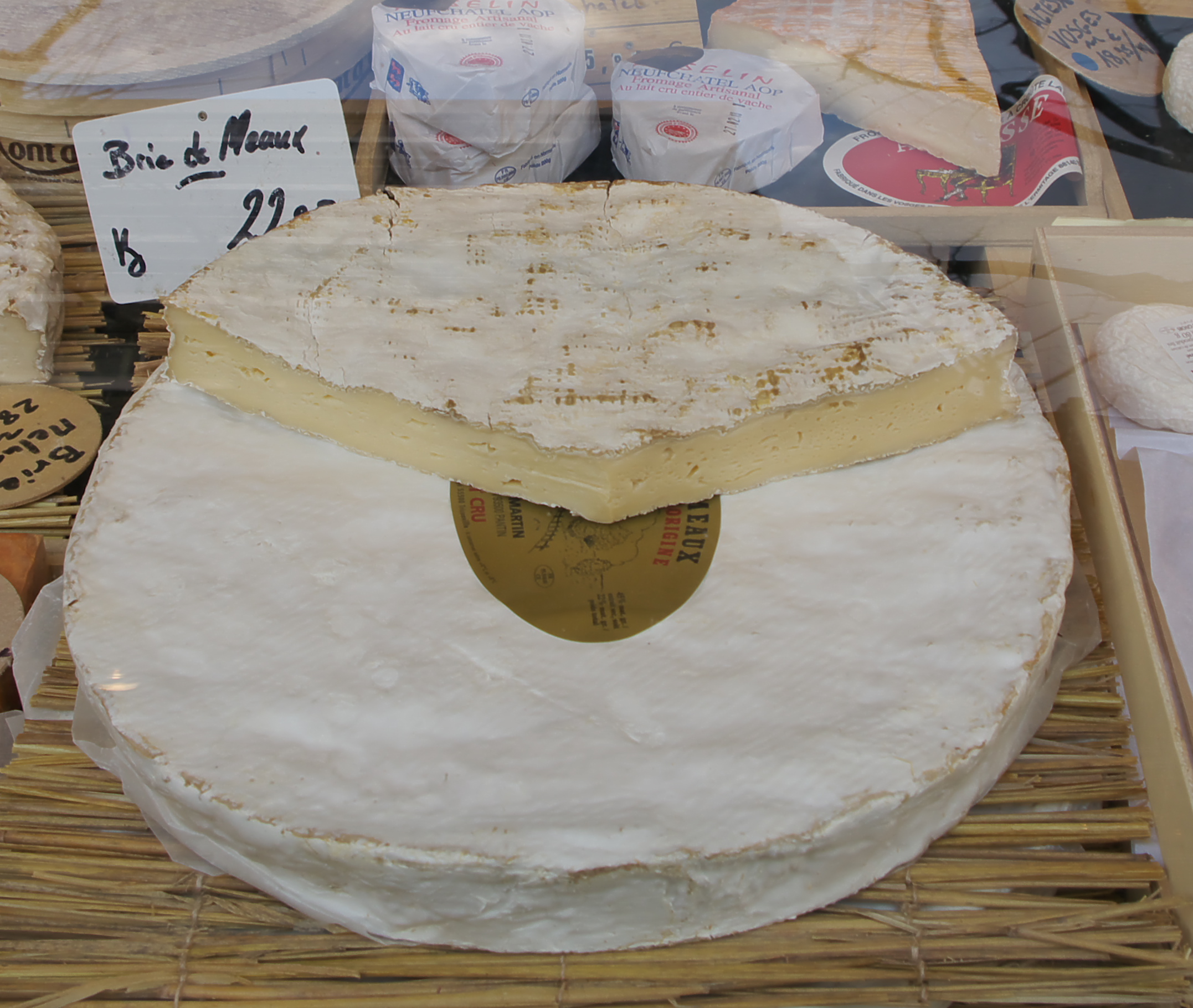 市場の台に置かれた大きなブリー・ド・モー、「Brie de Meaux」の札
