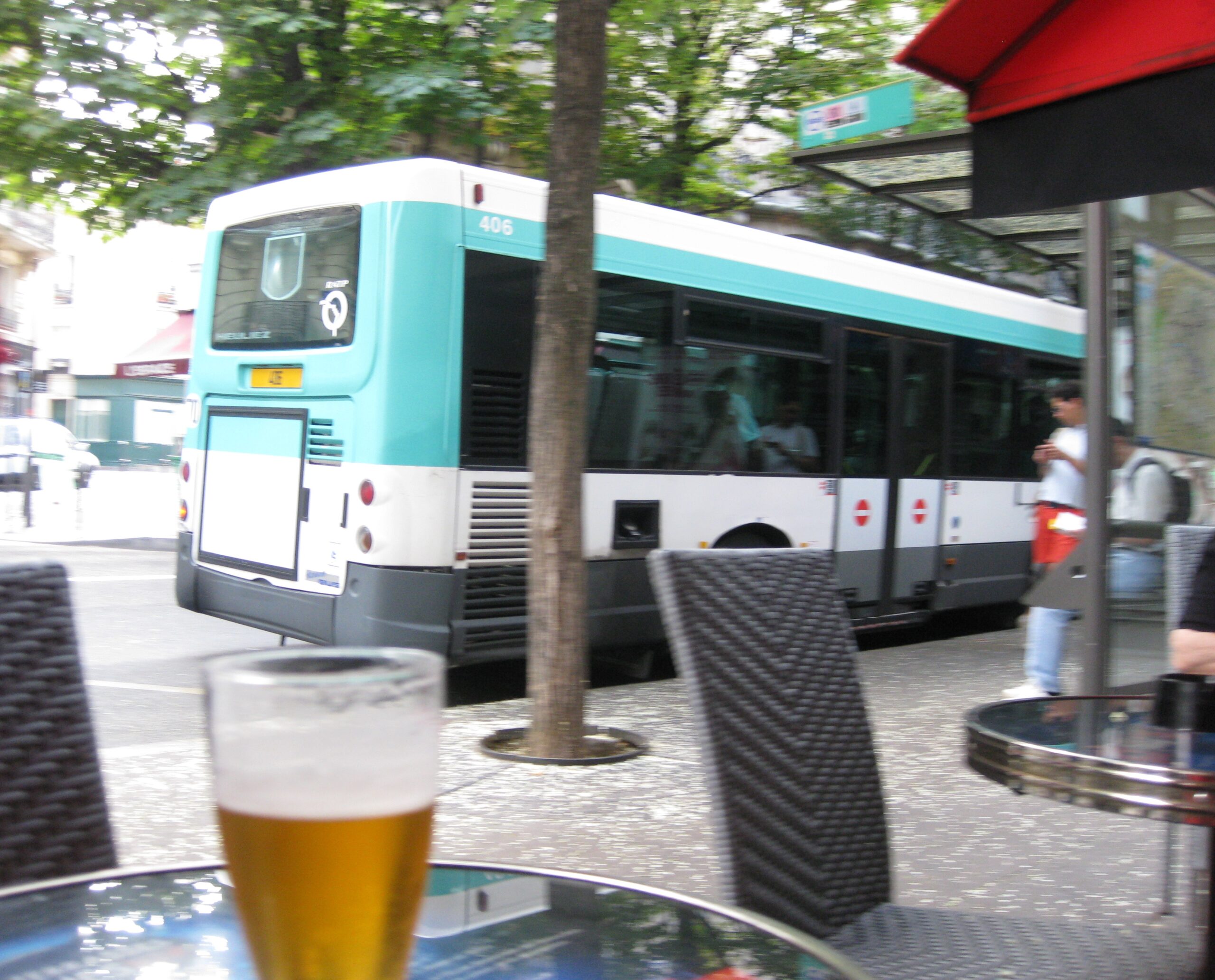 パリのカフェのテラス席の生ビール、奥に路線バス