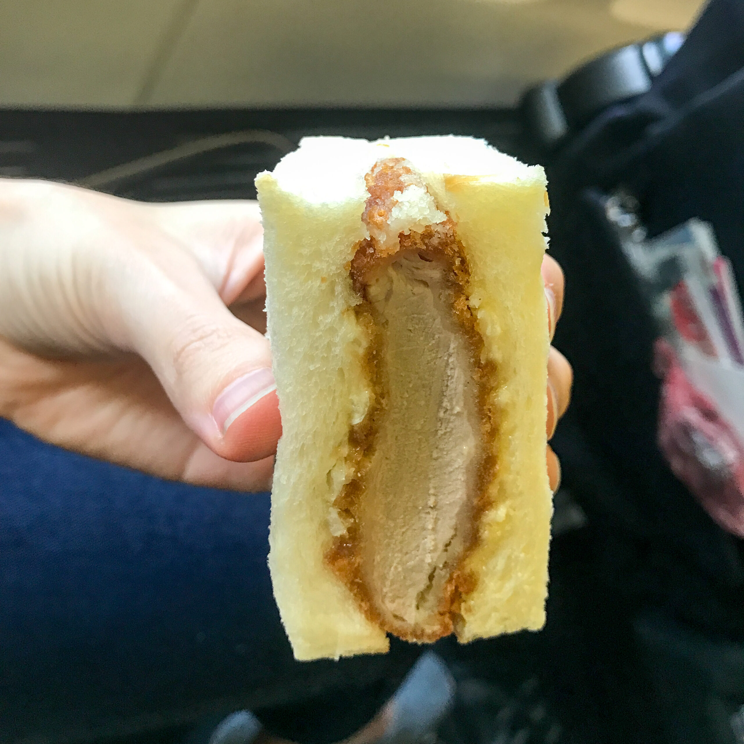 手に持った厚切りカツサンドの断面。白い食パン