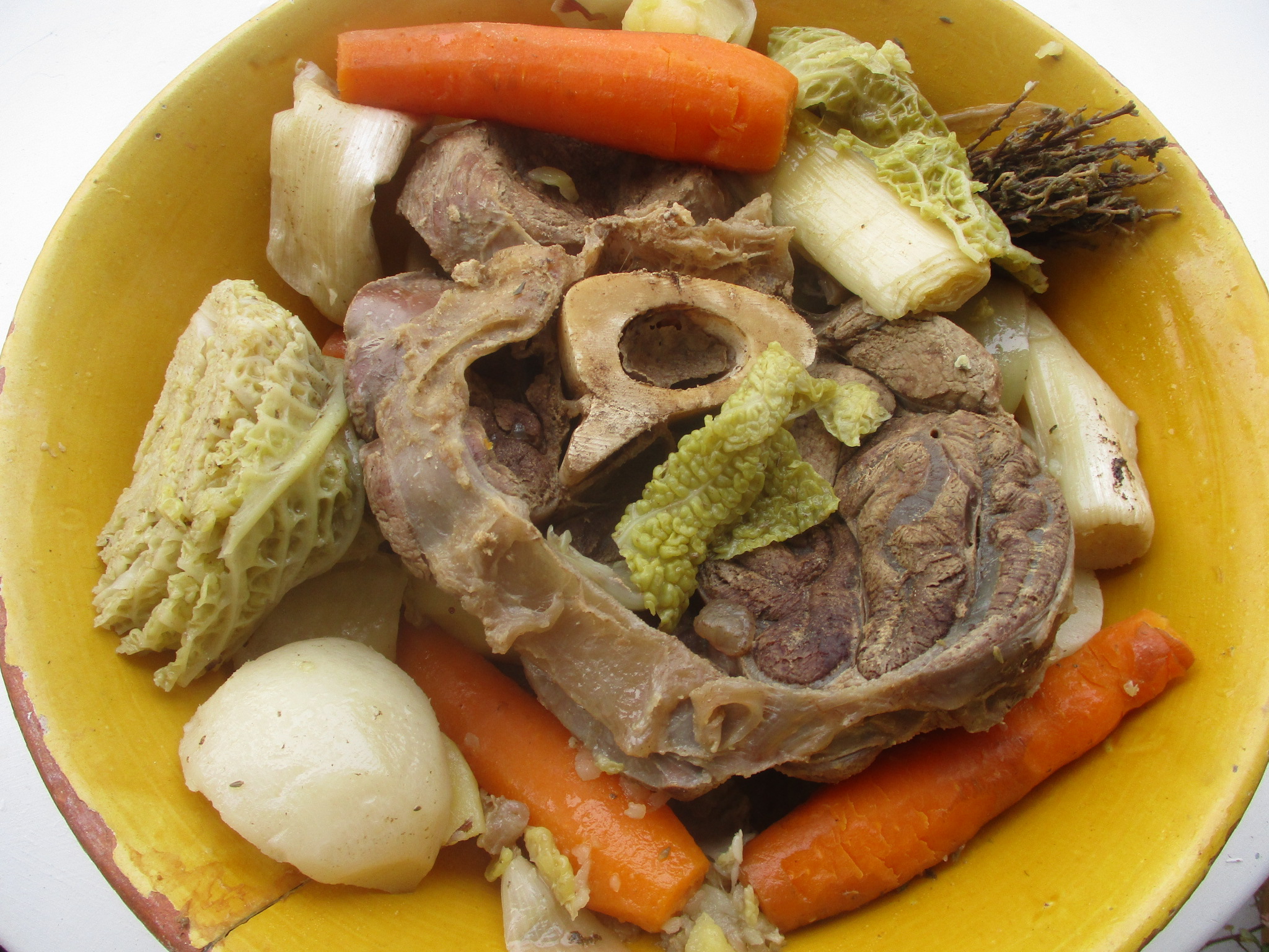 皿に盛った牛肉と骨、キャベツ、にんじん、じゃがいも