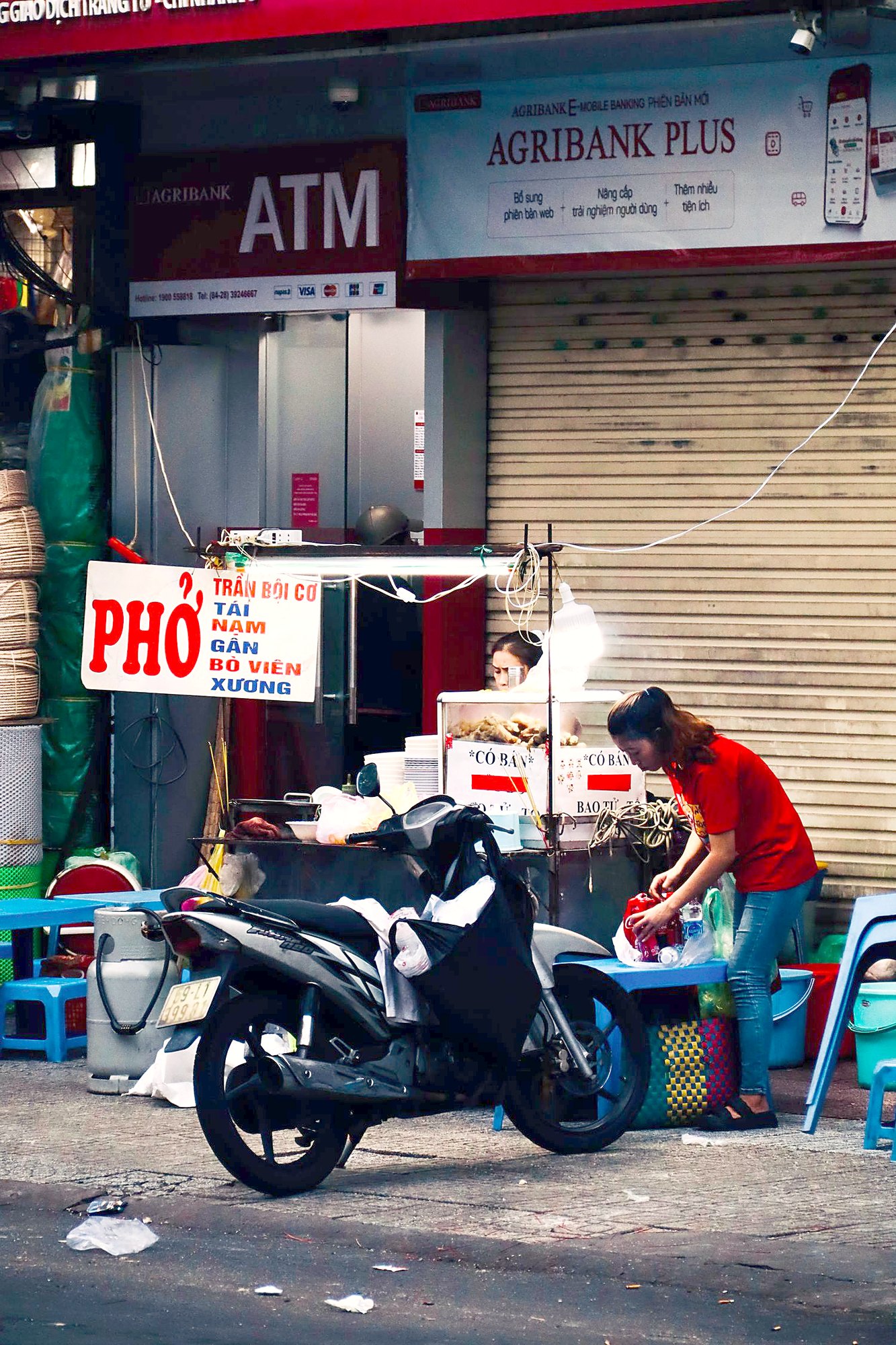 路上の店先。赤地に白でPHỞと書かれた看板が出ていて、手前にバイクが停まっている
