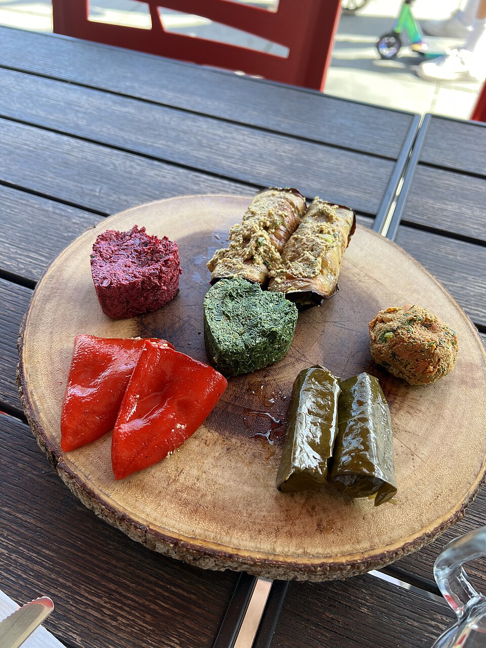 木の皿にビーツのプハリ、緑のプハリ、ドルマ、赤ピーマンが並ぶ