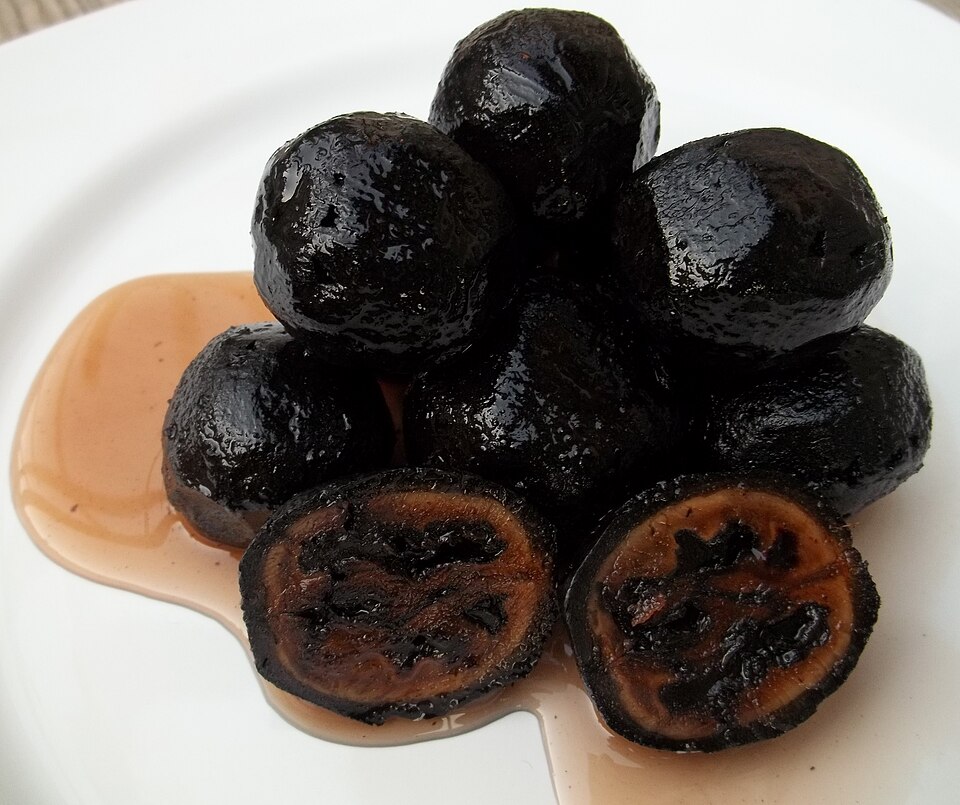 白い皿に積まれた、黒く艶のあるくるみの砂糖煮