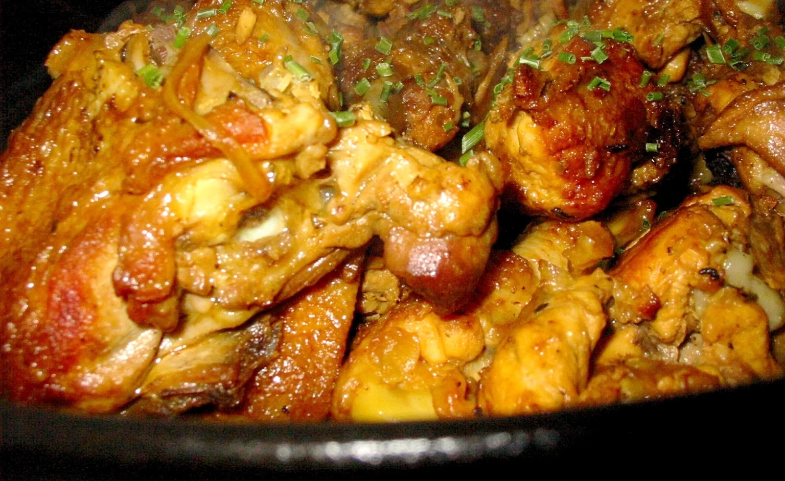 赤い煮汁をまとった鶏のカリのアップ