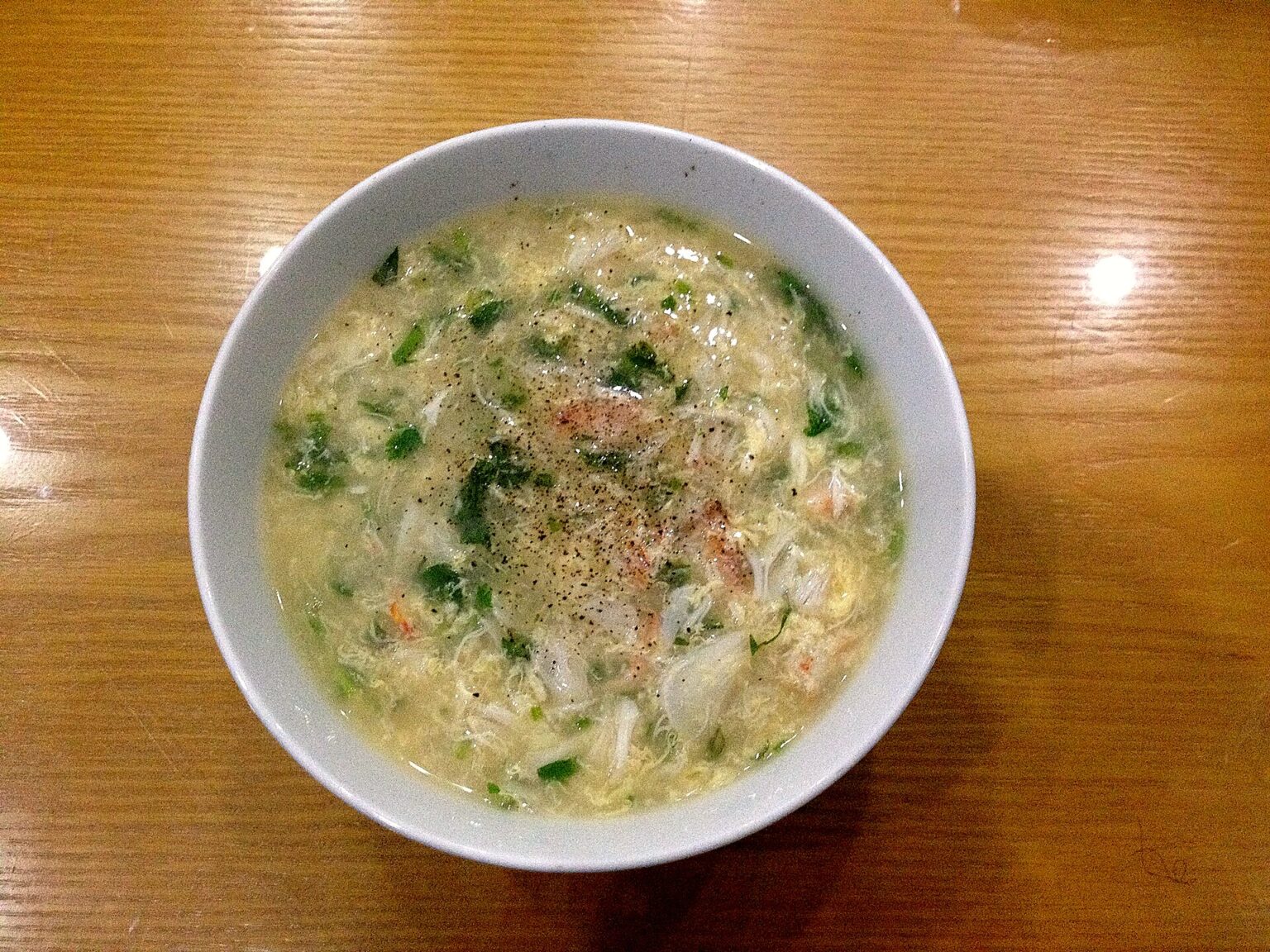 白い器に、とろみのついた白いスープ。ほぐした身、青ねぎ、黒こしょう