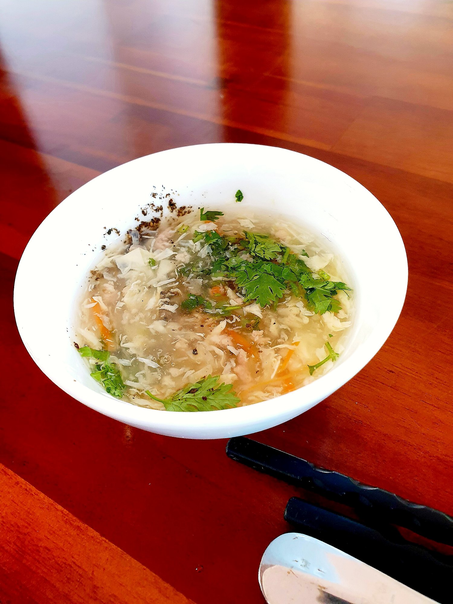 白い器のとろみのあるスープに、ほぐした身、にんじん、香菜、黒こしょう。ムイネーの宿の朝食で