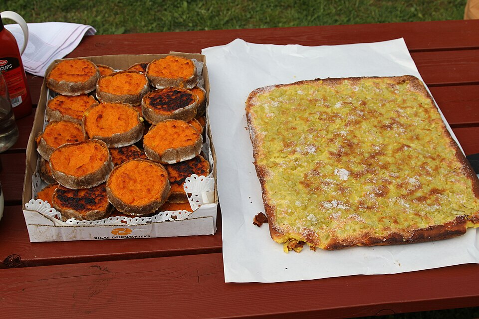屋外の赤い台の上に並べられた、箱入りのスクランドラウシスとルバーブのケーキ