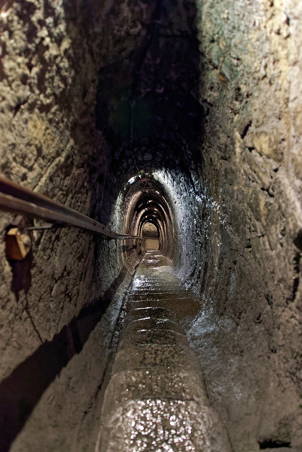 岩を掘り抜いた狭い坑道の床を流れる水