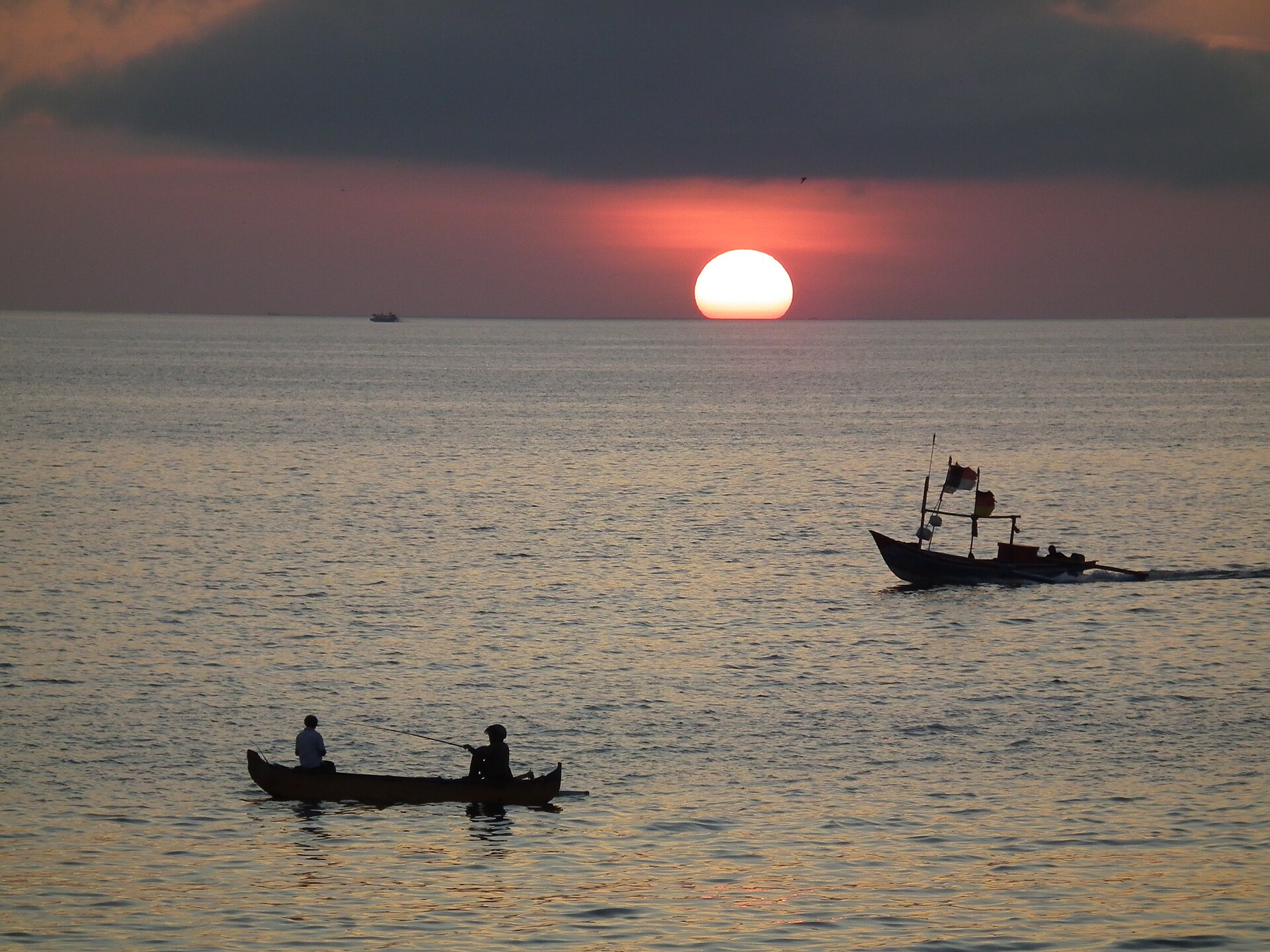ジンバランの海に沈む夕日と小舟