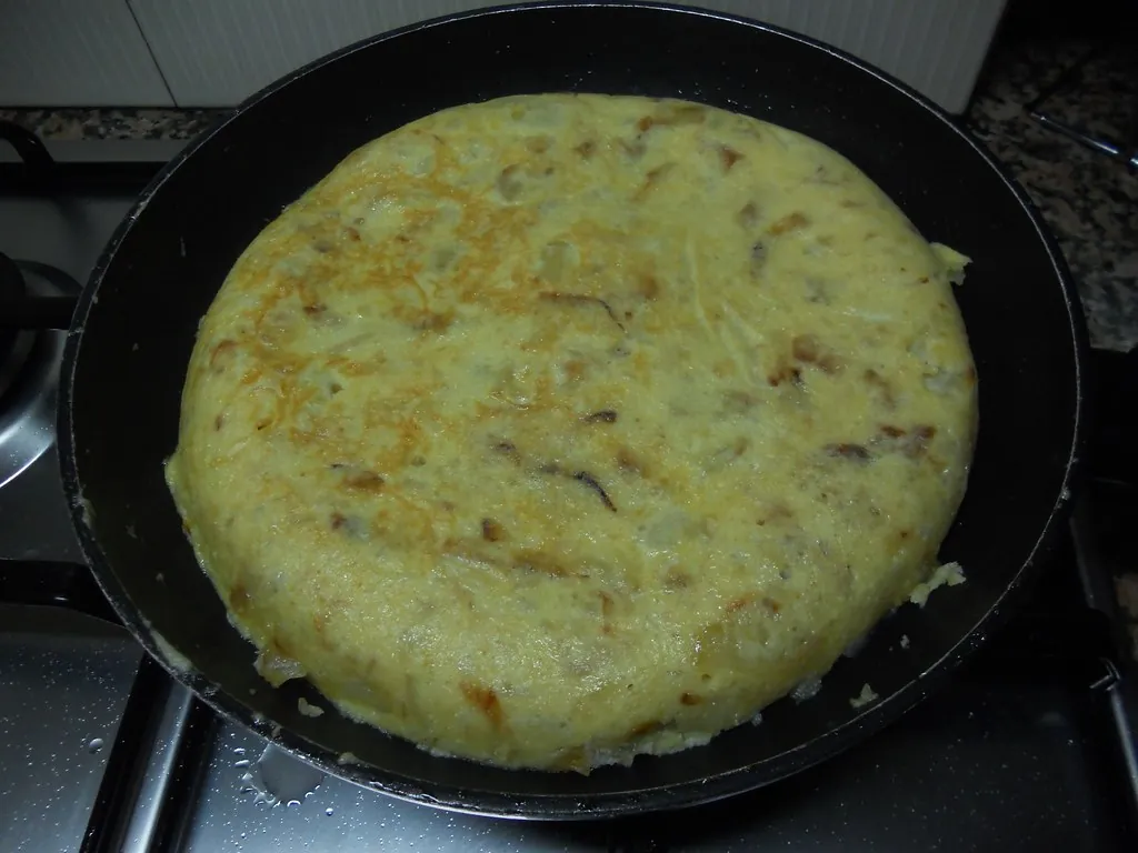 フライパンで焼いている玉ねぎ入りのトルティージャ